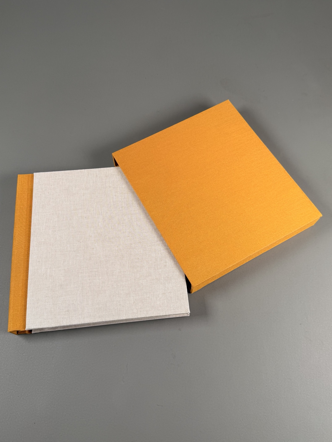 Handmade cream album with an orange spine beside a matching orange slipcase
